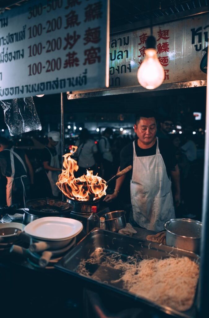 man cooking front of food stall